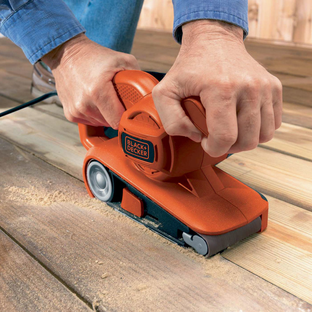 A man sanding wood floors using the Black+Decker 720W Belt Sander