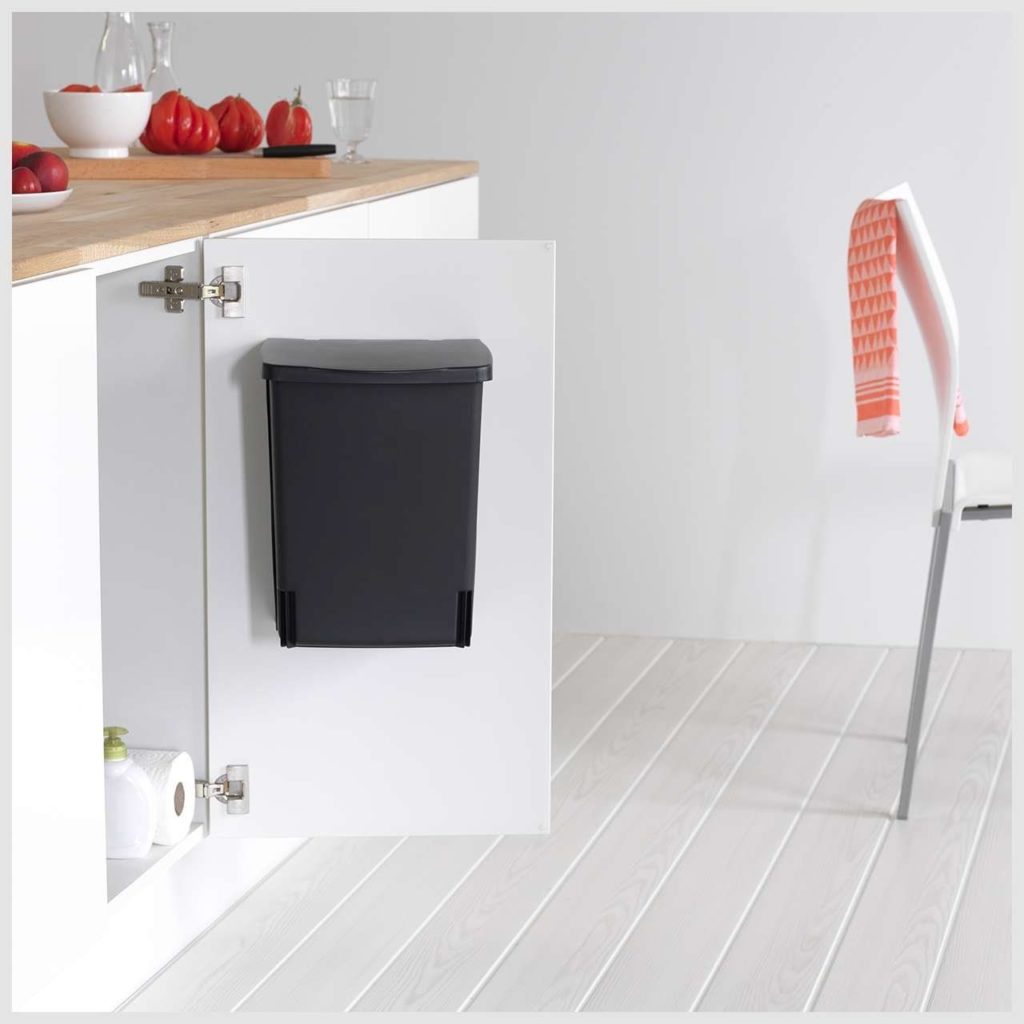 White kitchen cabinet open with a black bin  mounted to the inside of door
