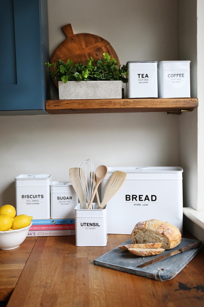 A kitchen counter with multiple white storage boxes on top