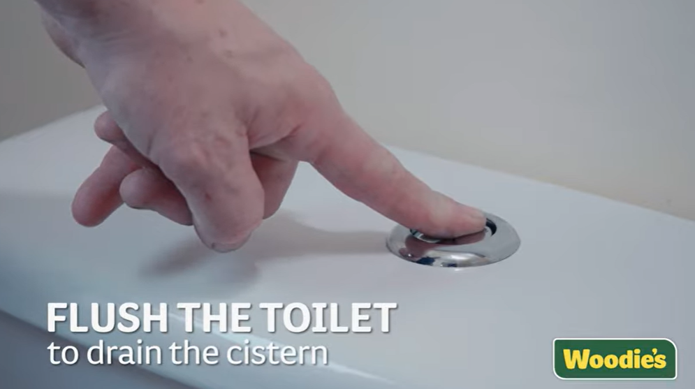 A man flushing the toilet to drain the cistern.