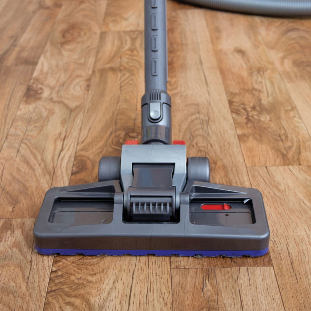 A vacuum being used on wooden floors.