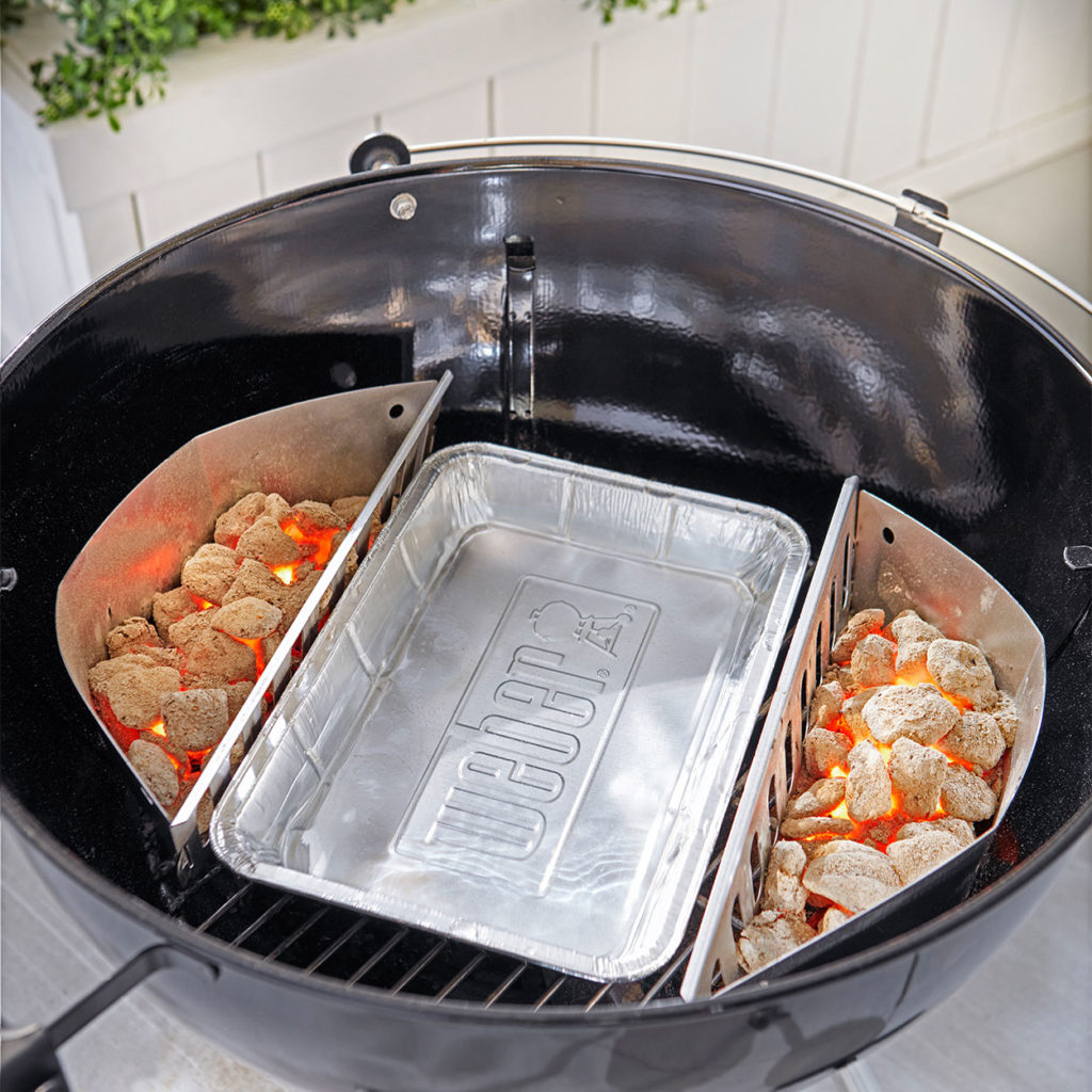 Close up of drip pan in the middle of bbq with charcoal either side