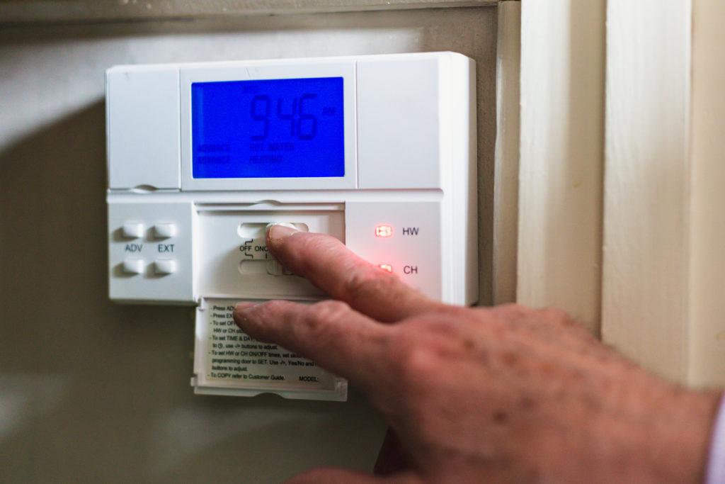 A senior man turning off his heat at home, to bleed his radiator.