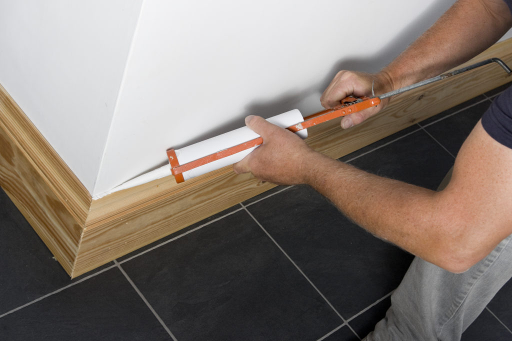 Man caulking wooden skirting.