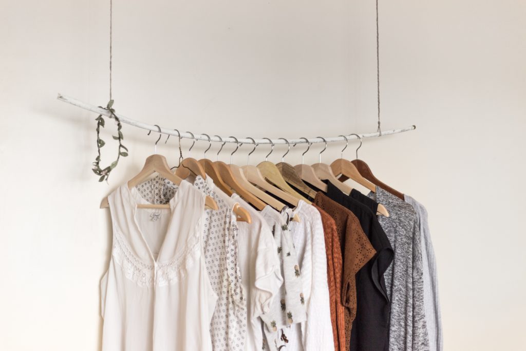 A freestanding clothes rail hanging from the ceiling with clothes hanging on the rail