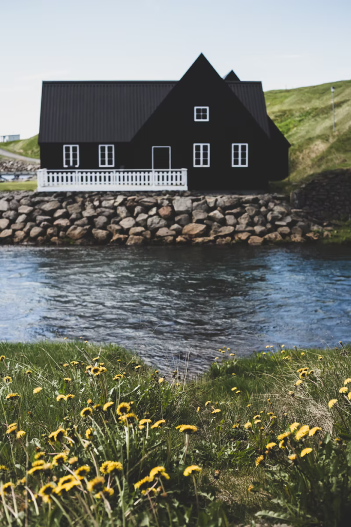 A home on a small creek is painted a black exterior paint colour to add drama and intensity to the home.