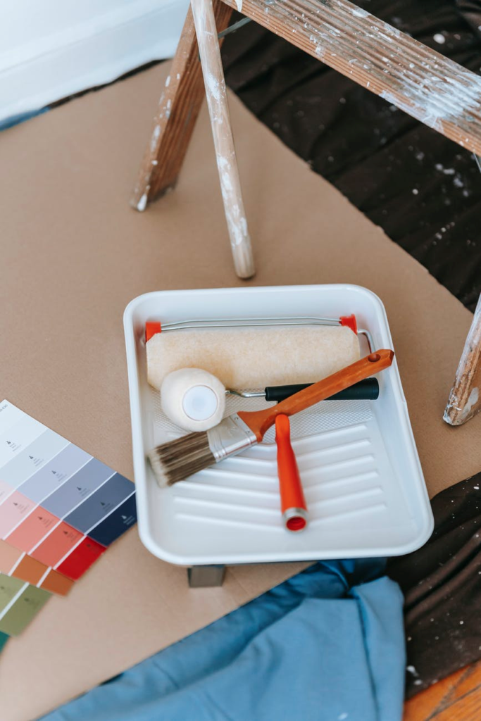 A roller and paintbrush lay in a tray, ready to be used to paint a ceiling.