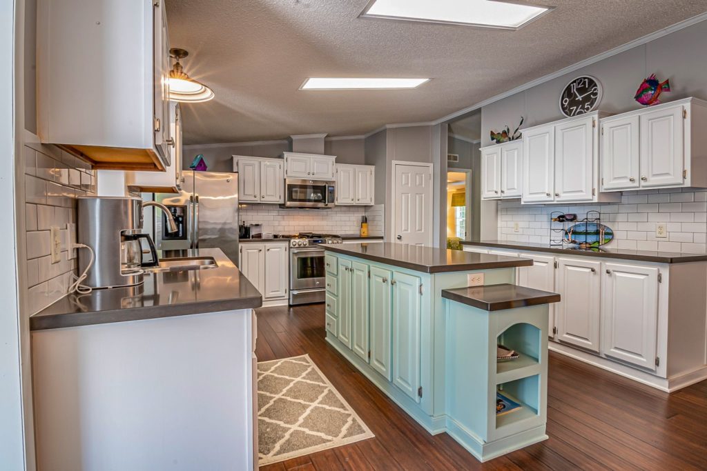 A white kitchen with a kitchen island pained in mint green