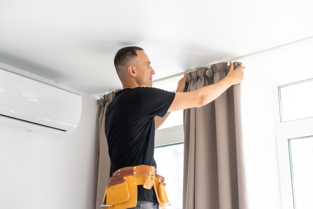 Image of a tradesman as he puts up a curtain pole