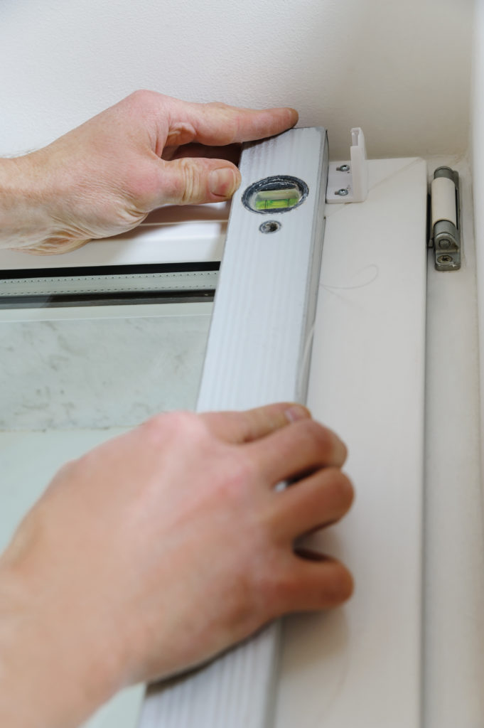 Man's hands holding level for installation the bracket correctly.