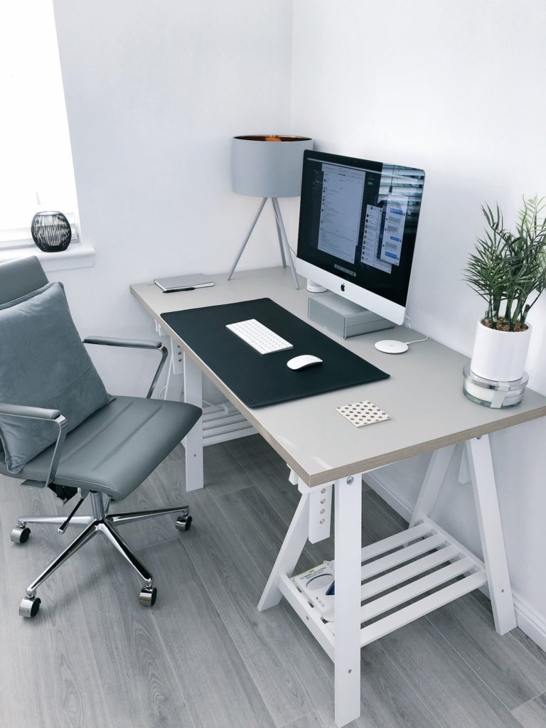 A home office setup with minimalist furniture like desk , chair and table lamp.