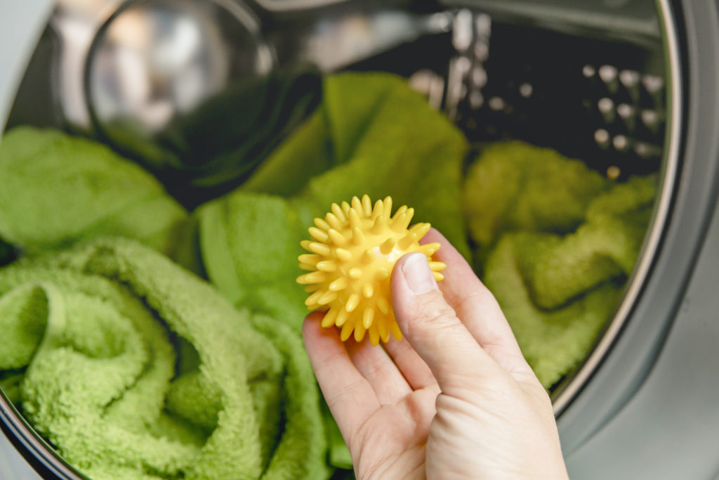 hand holding dryer ball infront of open washing machine