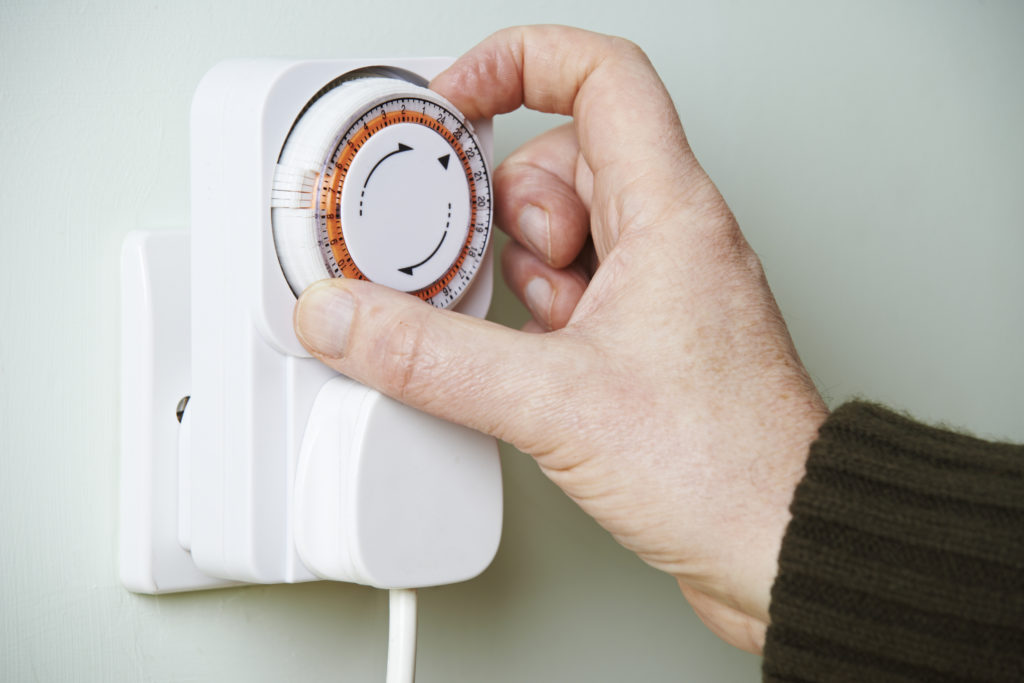 Man Adjusting Timer On Electrical Socket