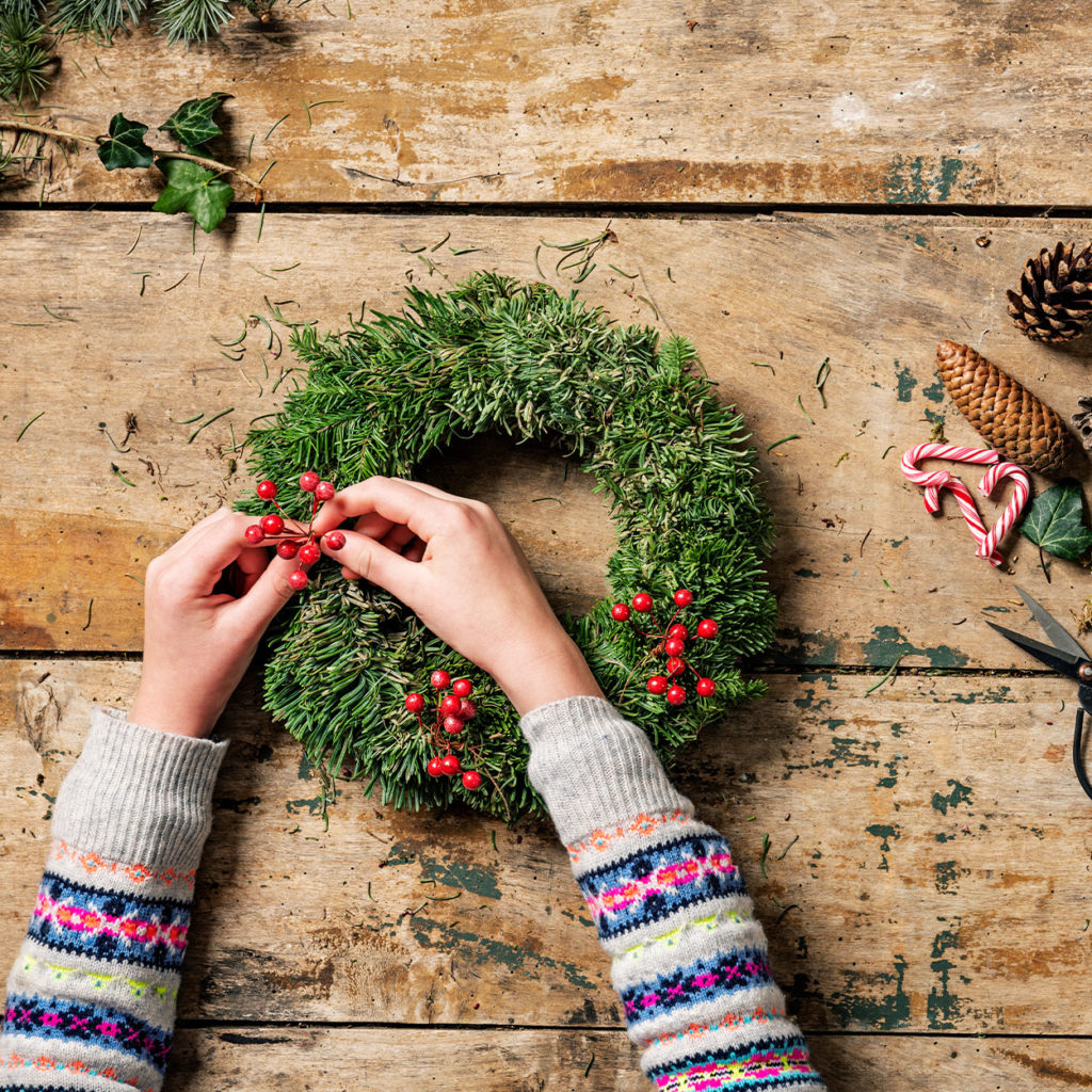 hands placing berries onto fresh wreath