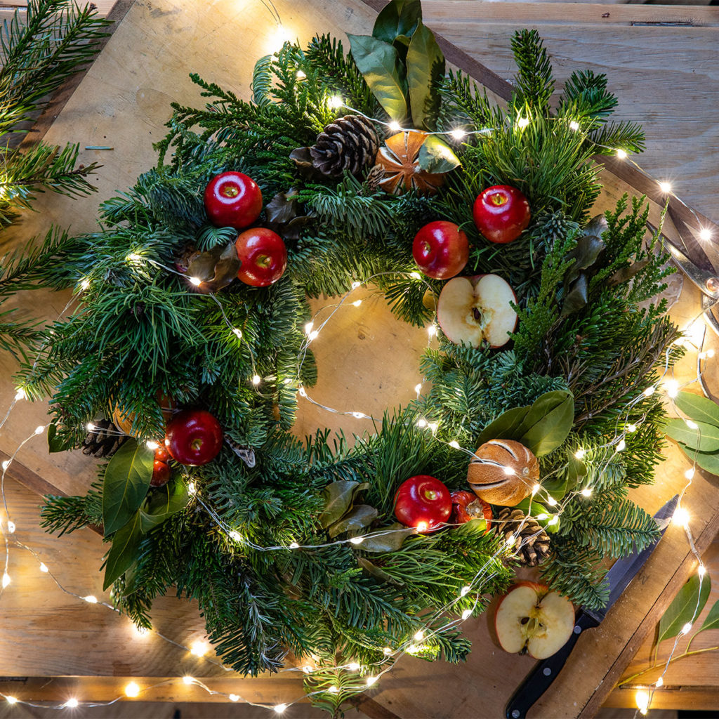 fresh wreath with dried apples, oranges,  pine cones and lights 