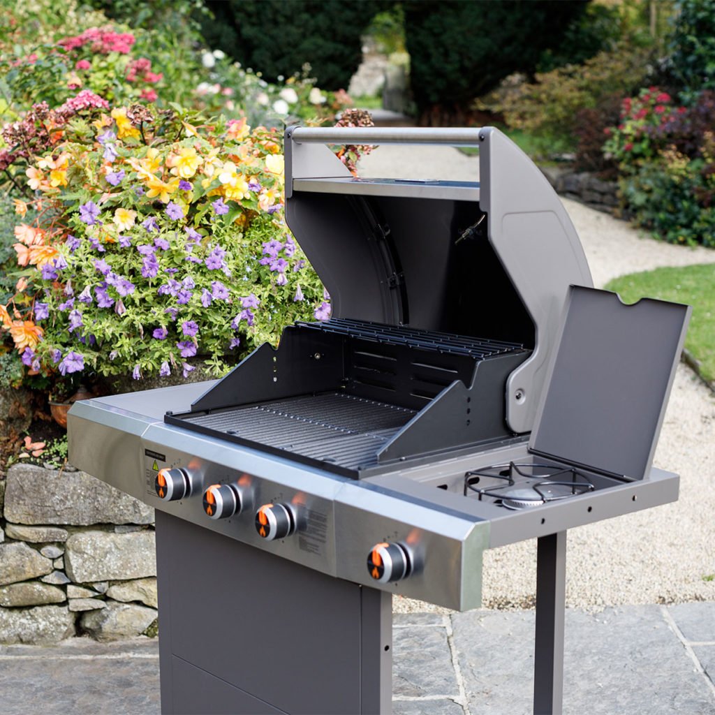 Gas BBQ in garden with lid of grill and side burner open
