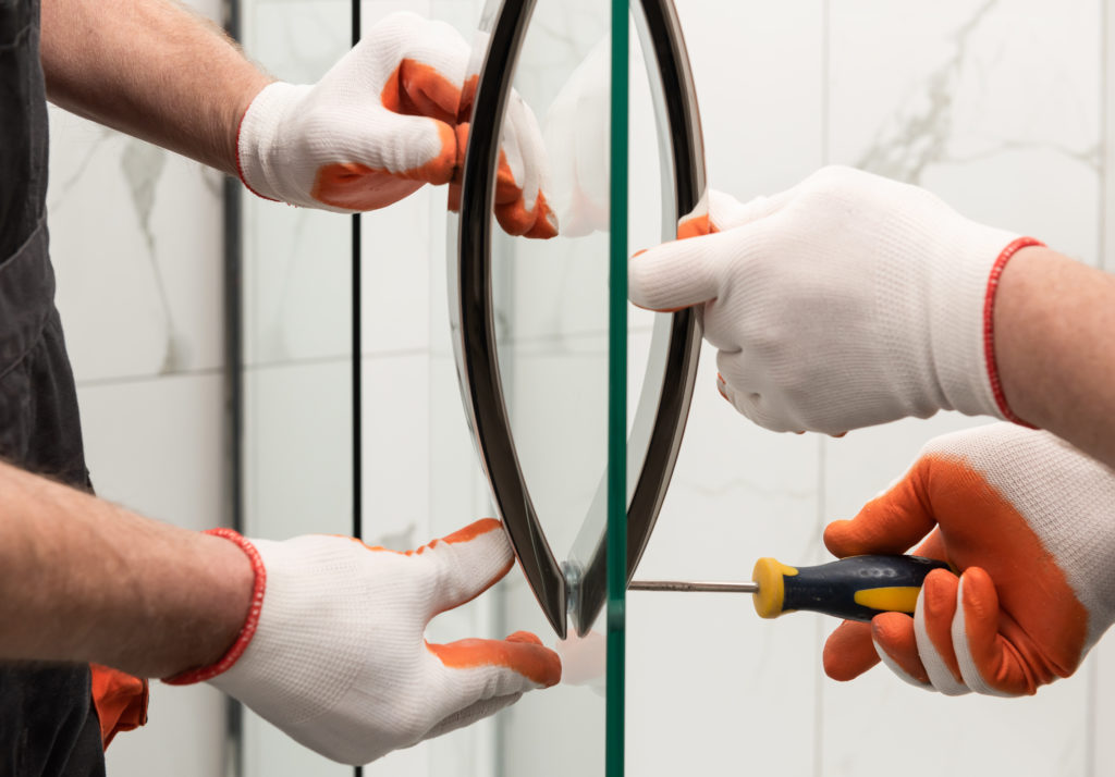 Hands using a screwdriver to secure handle onto glass