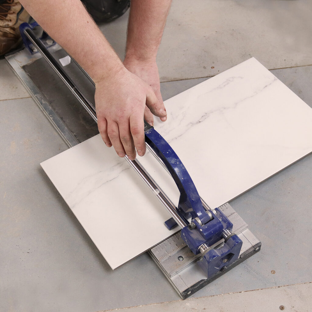 A manual tile cutter cutting a piece of tile