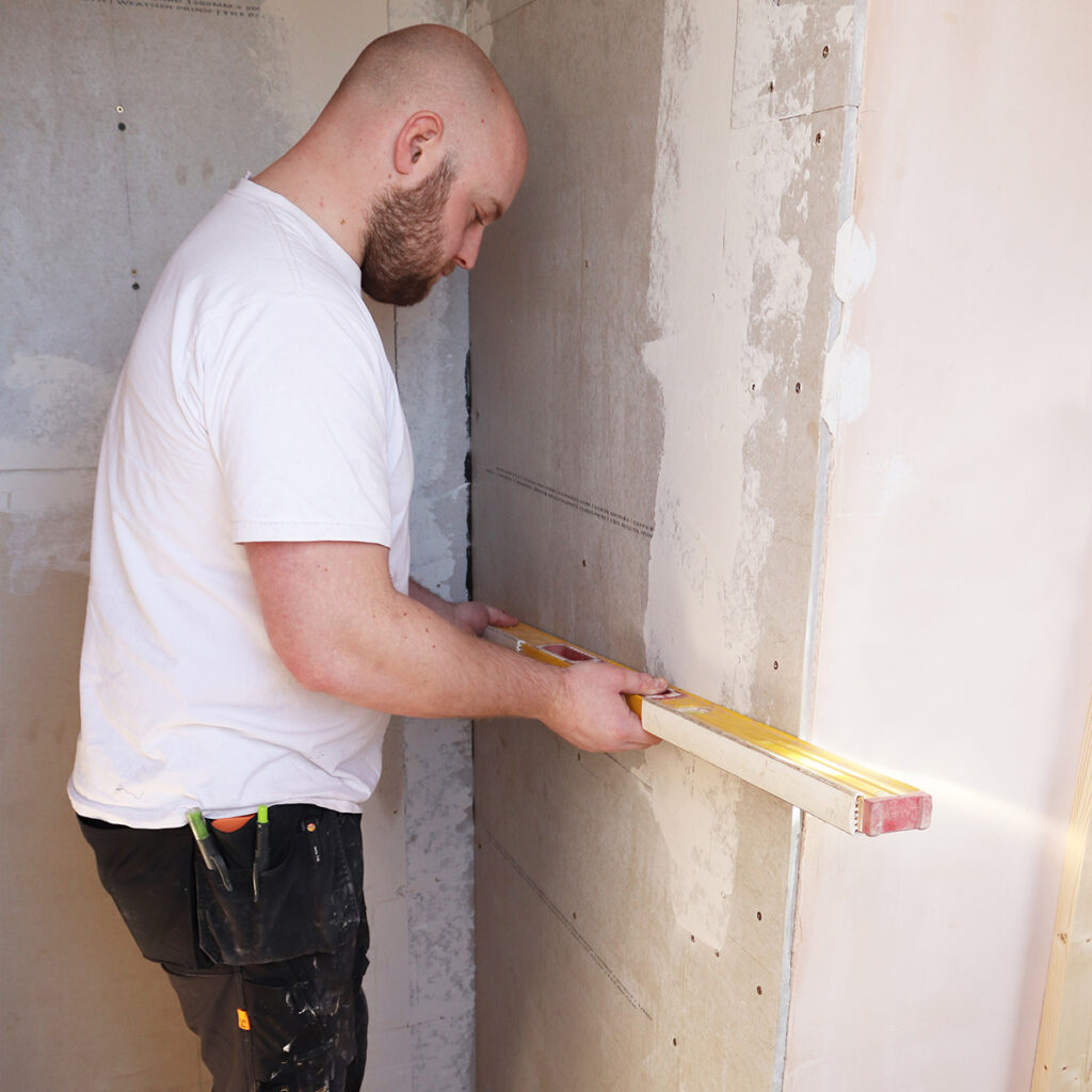 A man using a spirit level to make sure his tiles are straight