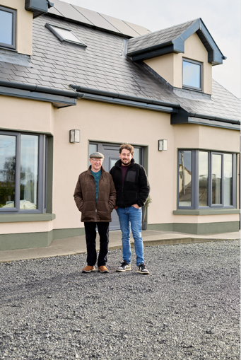 two men standing infront of their beige home