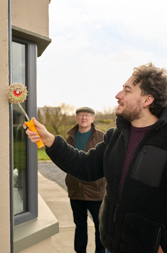 Two men painting a wall with a roller