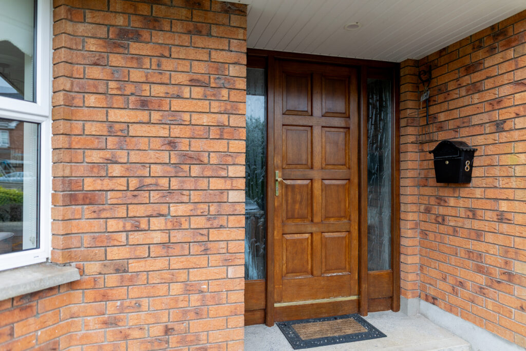 Brown wooden front door with decorative glass side panels before painting.