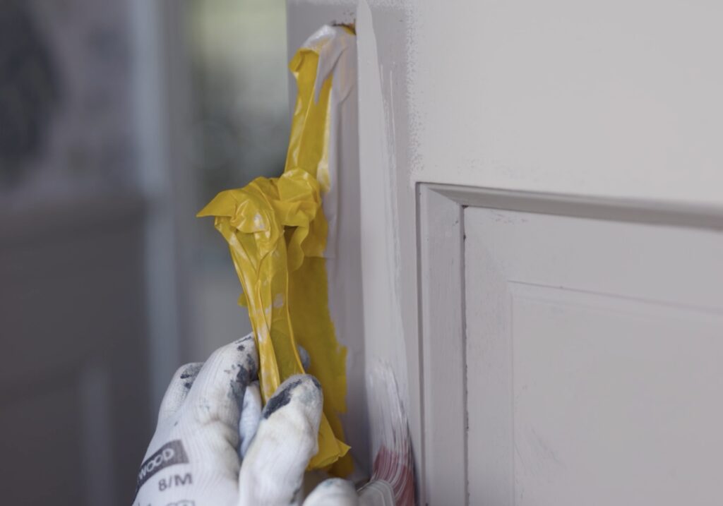 Peeling masking tape from the edge of a freshly painted front door.