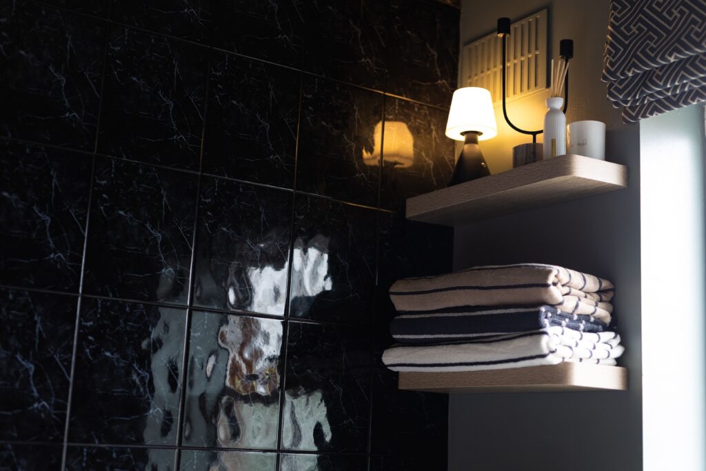 Image of a black bathroom with a shelf and towels